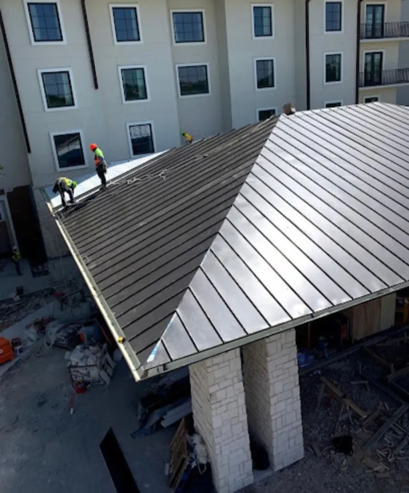 Crew installing standing seam metal roof panels on a commercial project in Lakehills